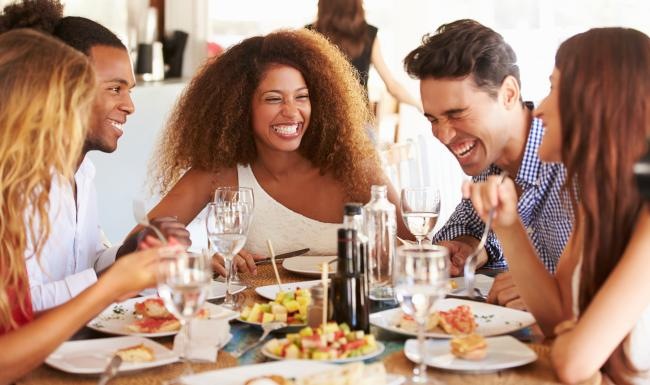 a group of people sitting at a table with food and drinks